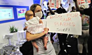 New mother Dr Dalene von Delft joins the Treatment Action Campaign in storming the stand of French multinational pharmaceutical company Sanofi. Delft, a multidrug-resistant tuberculosis (TB) survivor, holds a placard demanding the company ensures adequate supplies of its childhood TB vaccine are available worldwide. 